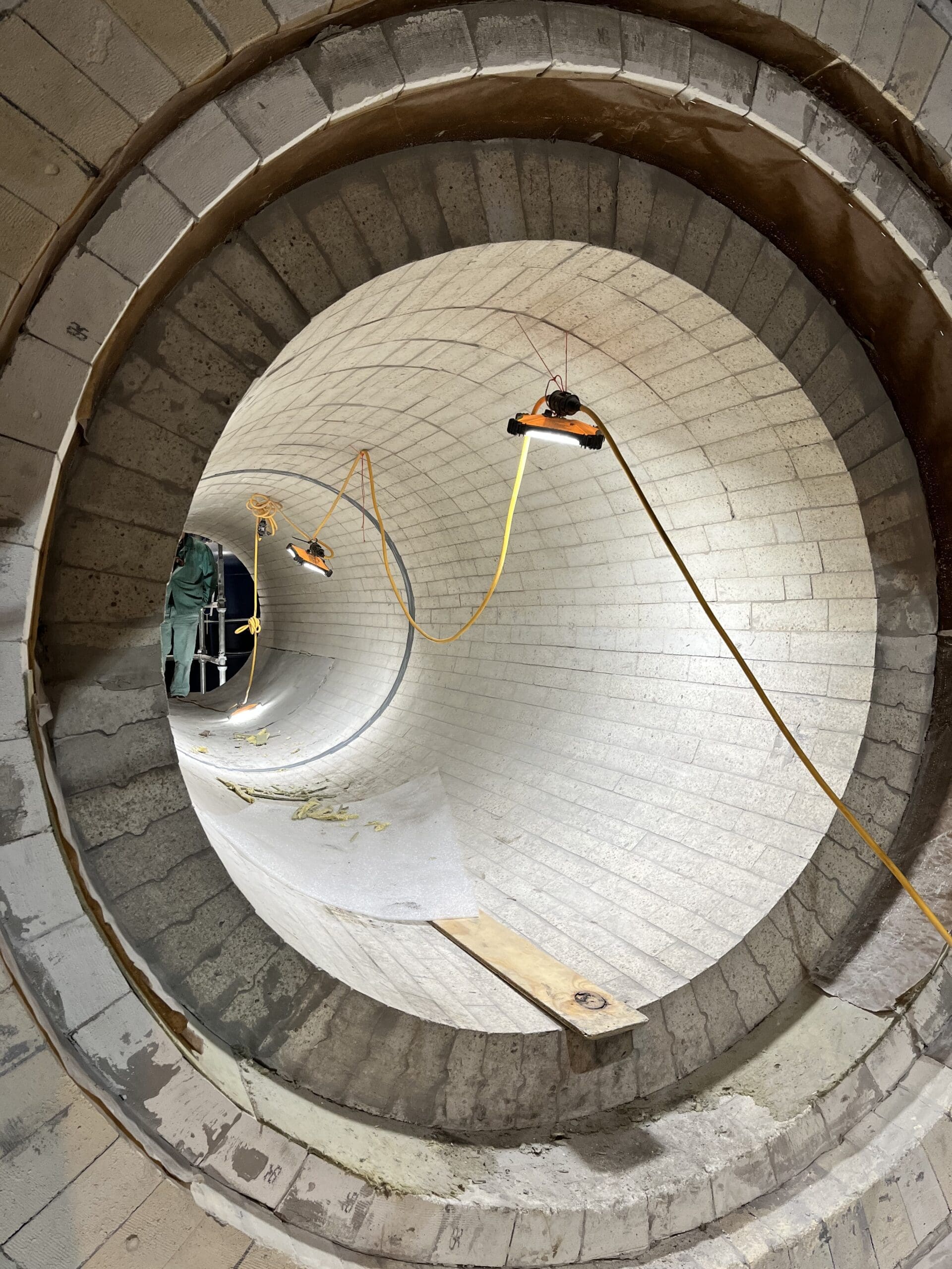 Interior view of a newly lined industrial kiln with hanging lights